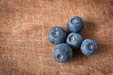 A close up shot of some fresh juicy blueberries on a wooden cutting board.