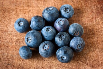 A close up shot of some fresh juicy blueberries on a wooden cutting board.