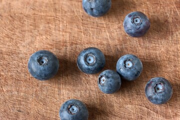 A close up shot of some fresh juicy blueberries on a wooden cutting board.