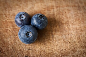 A close up shot of some fresh juicy blueberries on a wooden cutting board.