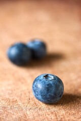 A close up shot of some fresh juicy blueberries on a wooden cutting board.