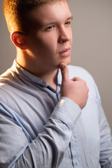 Body shaming. Obesity problem. Healthy diet. Weight loss. Portrait of thoughtful confused doubtful overweight chubby man in blue shirt with thumb on chin isolated on gray background.