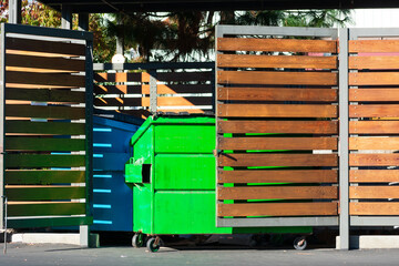 Two waste management blue and green garbage containers dumpsters in garbage enclosure used for...