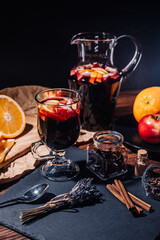 Still life - mulled wine, hot red wine with spices in glass among fruits. Scented cozy Christmas celebration, fragrant punch concept.
