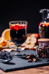 Still life - mulled wine, hot red wine with spices in glass among fruits. Scented cozy Christmas celebration, fragrant punch concept.