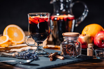 Still life - mulled wine, hot red wine with spices in glass among fruits. Scented cozy Christmas celebration, fragrant punch concept.