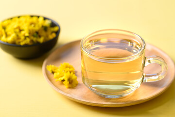 Organic Chrysanthemum flower tea in a cup on yellow background, Healthy Herbal drink