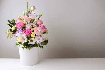 mock up bouquet of roses, daisies, lisianthus, chrysanthemums, unopened buds in a white paper box on a white table and wall.