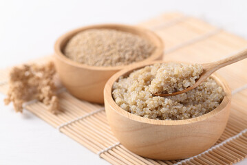 Cooked brown quinoa seeds in a wooden bowl with spoon for eating, Healthy vegan food
