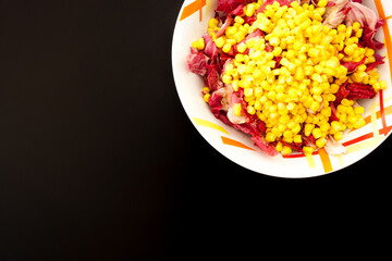 Salad with corn on black table, top view