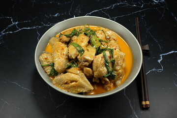 Steamed chicken with red curry and basil serving in the bowl. Famous traditional spicy chicken in Thai style. 