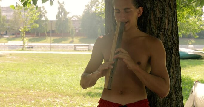Young man playing flute folk music outdoors