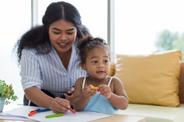 Happy African American mother and her little daughter. Mother teaching her daughter drawing and...