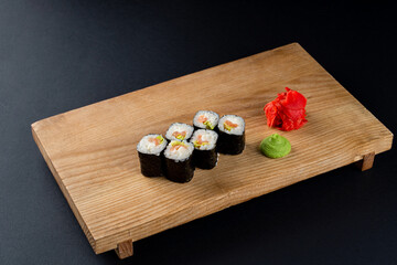 Classic cucumber and lettuce sushi rolls on wooden board, six rolls set on board