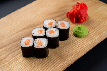 Simple salmon sushi rolls served on wooden dish, minimalist studio photo for a menu