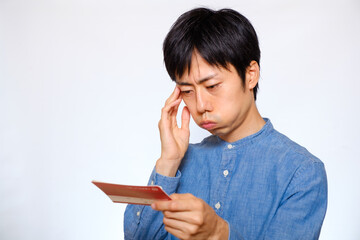 預金通帳を見て心配そうな顔をする日本人男性