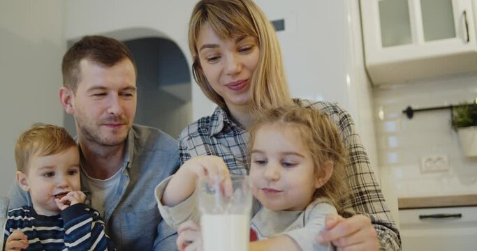 Young family spending time at home together. Parents with children eating traditional homemade gingerbread christmas cookies pastry in the kitchen. Cute kids eat biscuits with milk.