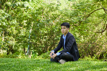Naklejka na ściany i meble Young businessman relaxing in the garden