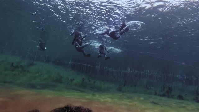 Team of Divers exploring natural limestone sinkhole pond in Australia.