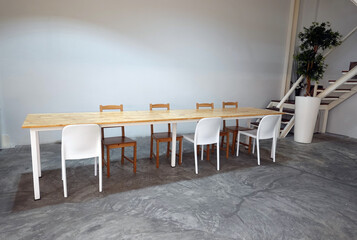 Room with wood long dining  table and white chairs.    