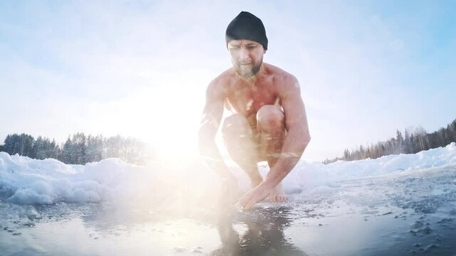 Winter swim. Young man swims in the winter lake. Splitted footage with underwater view of the icy water