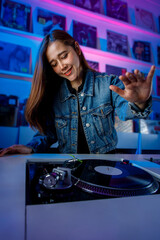 chica dj alegre mezclando pistas con discos de vinilo usando un tornamesa y una mezcladora en una tienda de discos.