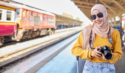 Female Islamic tourists hold cameras while waiting to travel.