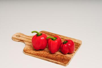 カッティングボード上に3個の赤いパプリカ