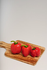 カッティングボード上に3個の赤いパプリカ