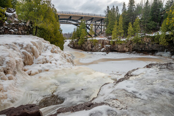 Arch bridge over a river covered with snowdrifts