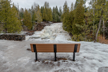 Small frozen waterfall and river covered with snowdrifts