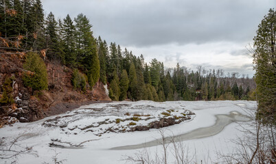 Small frozen river covered with snowdrifts