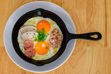 Fried eggs in a black pan placed on a wooden table