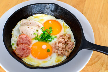 Fried eggs in a black pan placed on a wooden table