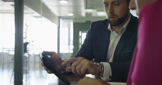 Young business man and woman inside office discussing over ipad mid coffee break
