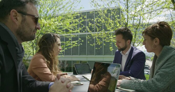 Two Businessmen And Two Business Woman Having A Team Meeting Discussing Outside Offices In Nature