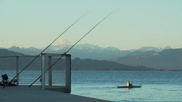 canoeing on Bodensee, fishing rod, mountains and sunset