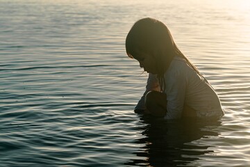 A depressed little girl sitting outside on the beach. Sad children.