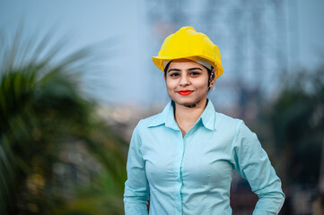 Close up portrait of beautiful female engineer wearing a protective helmet and looking at camera.