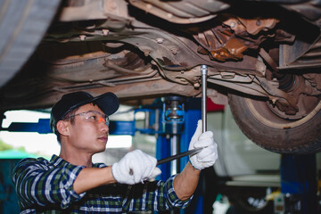 Asian engine mechanic at car suspension repair work