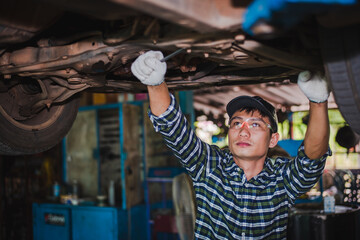 Asian engine mechanic at car suspension repair work