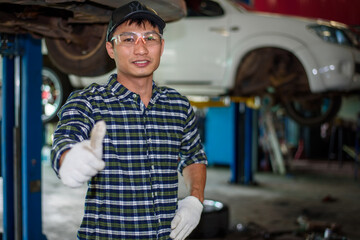 Asian auto mechanic works car repairs at his own repair shop.