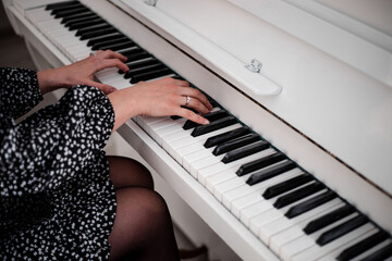 Beautiful female hands over the piano keys. A white musical instrument.