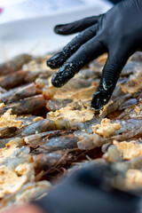 camarones partidos por la mitad  a la mantequilla  preparados y acomodados en el grill por manos de chef  con guantes de látex negro 