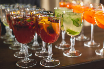 View of alcohol setting on catering banquet table, row line of different colored alcohol cocktails on a party, martini, vodka, spritz and others on decorated catering table event