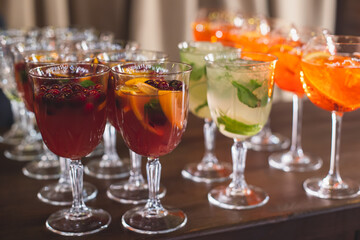 View of alcohol setting on catering banquet table, row line of different colored alcohol cocktails on a party, martini, vodka, spritz and others on decorated catering table event