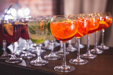 View of alcohol setting on catering banquet table, row line of different colored alcohol cocktails on a party, martini, vodka, spritz and others on decorated catering table event