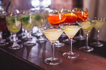 View of alcohol setting on catering banquet table, row line of different colored alcohol cocktails on a party, martini, vodka, spritz and others on decorated catering table event