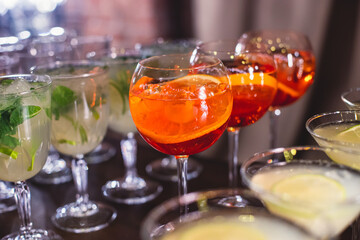 View of alcohol setting on catering banquet table, row line of different colored alcohol cocktails on a party, martini, vodka, spritz and others on decorated catering table event
