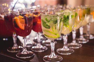 View of alcohol setting on catering banquet table, row line of different colored alcohol cocktails on a party, martini, vodka, spritz and others on decorated catering table event